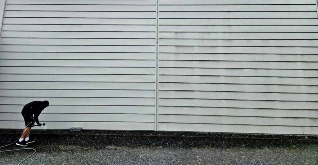 Medarbejder fra Jysk Vinduespudsning er igang med at rengøre og rense en facade